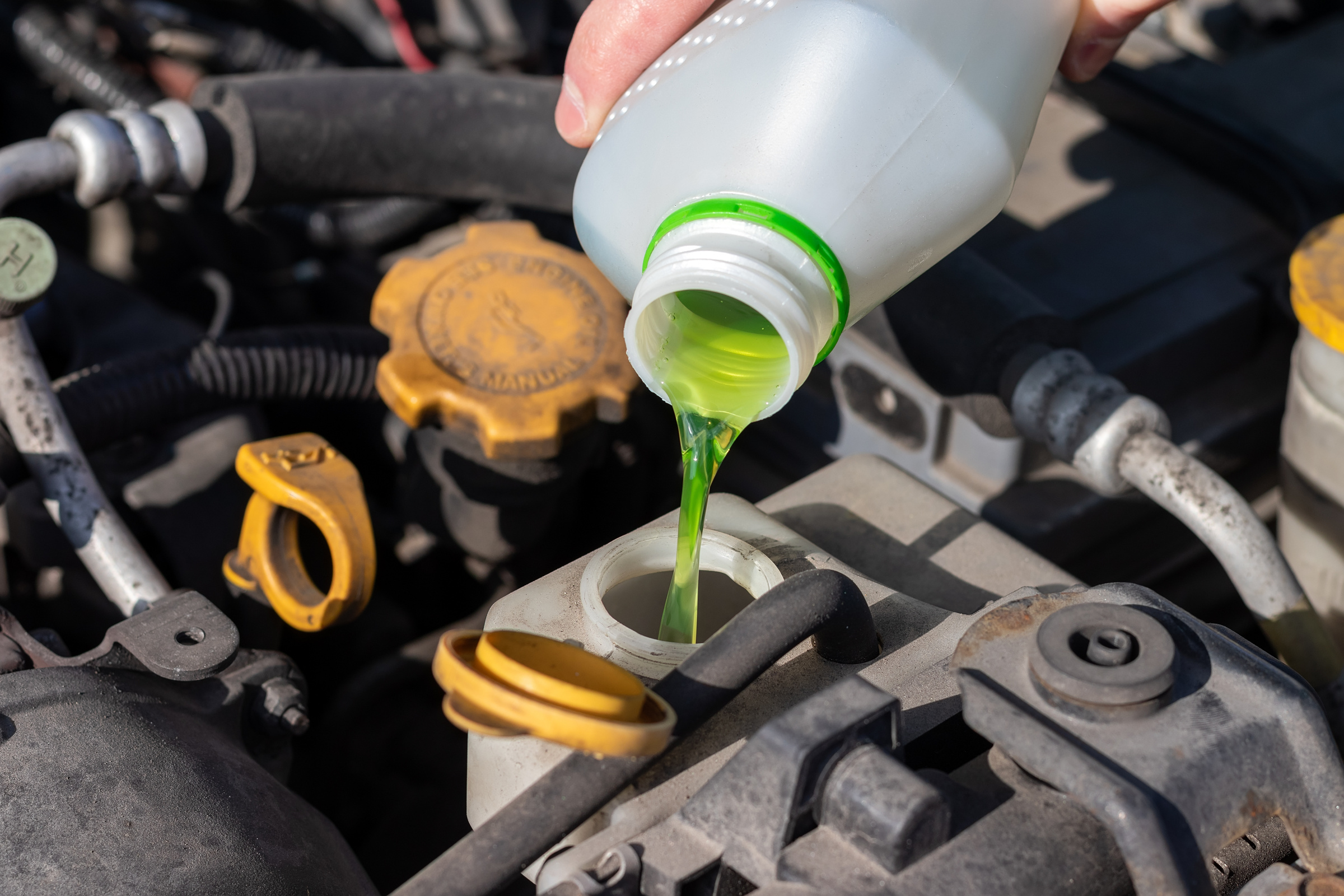 Hand with Bottle Pouring Antifreeze Coolant into Expansion Tank